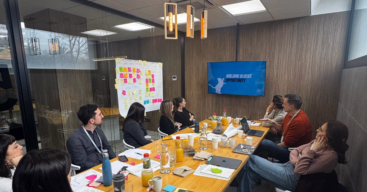 Two people annotating a large kitchen journey mapping sheet with sticky notes and printed research artefacts on a warmly lit table.